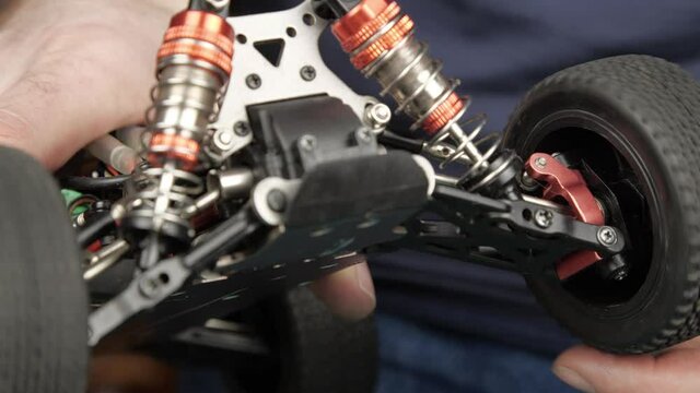 Close-up radio control model buggy car. The hands of the master checking the front wheels of model