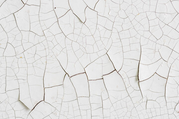 Peeling paint on the wall. Old concrete wall with cracked flaking paint. Weathered rough painted surface with patterns of cracks and peeling. Grunge texture for background and design. High resolution.