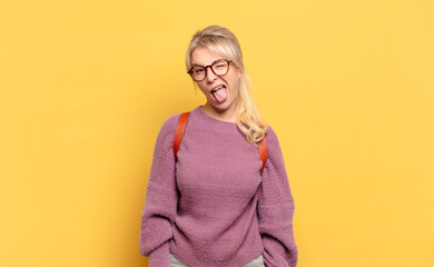 blonde woman with cheerful, carefree, rebellious attitude, joking and sticking tongue out, having...
