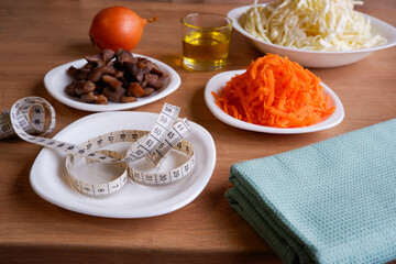 Healthy eating. Vegan food. Mushrooms, raw, chopped vegetables for salad on white plates. Cabbage, carrots, onions. Olive oil.