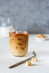 Glass of coffee with ice, milk on a light background. Cold summer drink, Iced coffee.