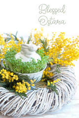 Obraz na płótnie Canvas Blessed Ostara. Easter bunny with fresh cress salad and mimosa flowers on table. festive spring season. wicca pagan tradition. spring equinox holiday