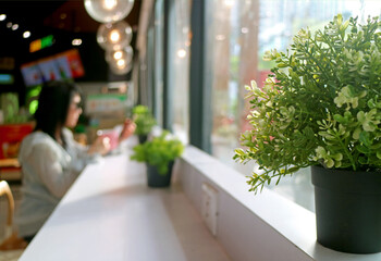 Closeup a potted plant with blurry woman drinking coffee and relaxing alone 
