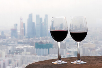 Glasses with red wine on the background of the city. Rendezvous for two at the rooftop restaurant. Restaurant overlooking downtown. Romantic setting, Moscow, Russia