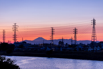 Obraz premium 夕焼けの中、富士山と送電塔のシルエット、青い空を映す水面