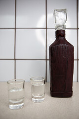 
bottle of vodka with glasses on the table in the kitchen