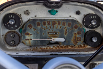 Gauge cluster on a rusty old abandoned vintage automobile showing temperature, gas, and speedometer
