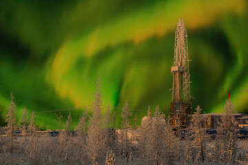 The rig and the northern landscape of the oil and gas field against the polar lights. Landscape with beautiful night sky in winter in the Arctic