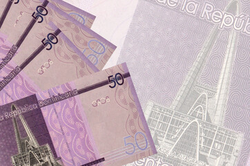 50 Dominican pesos bills lies in stack on background of big semi-transparent banknote. Abstract business background