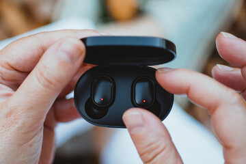 Close-up of a woman taking out a wireless earbud from his charging box