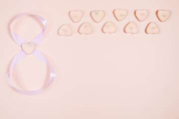 March 8, composition of hearts on a pink background. View from above.