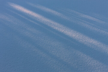Naklejka na ściany i meble Shadows in the fresh snow. Snow texture, natural background.