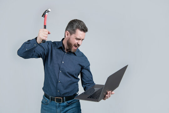 Yelling engineer break laptop computer with hammer grey background, frustration