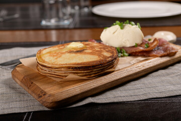 Pancakes with bacon and cheese on a wooden board 