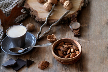 Obraz na płótnie Canvas cup of coffee, different kinds of nuts, walnut, hazelnuts, almonds on old wooden table boards, edible seed kernels, food concept, confectionery ingredient