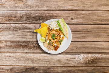 Pad Thai- traditional Thai dish. stir fried rice noodles with shrimps and vegetables on wooden background