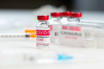 glass bottle with coronavirus vaccine on white table in clinic. Concept of treatment of coronavirus infection, COVID-19 vaccination