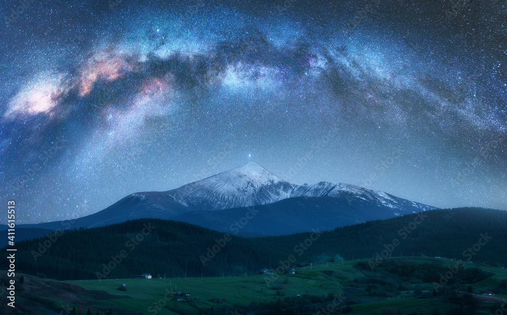 Wall mural arched milky way over the beautiful mountains with snow covered peak at night in summer. colorful la