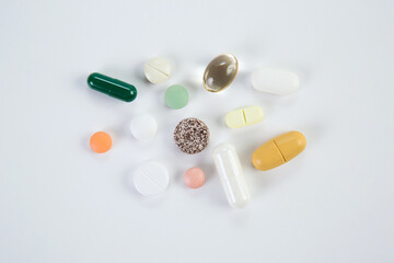 Different colored medicine and types of pills on a white background.