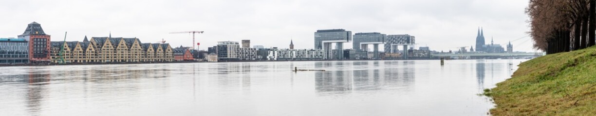 panorama of Cologne with crane houses and Cologne cathedral at snowy weather. rhine river with high water