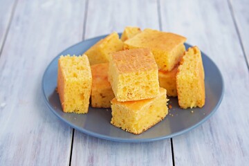 Sliced cornbread on a gray plate on a light wooden background. Corn flour recipes. 