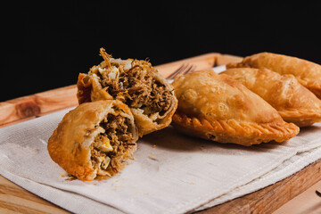 A caesina empanada opened in half, in front of more empanadas.