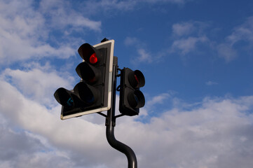 Traffic light on red against deep blue cloudy sky with copyspace