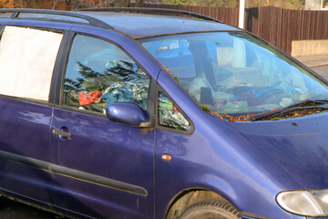 Fototapeta premium The detail of an abandoned broken car, now a wreck with damaged or broken windows and full of rubbish or waste. Occupies a parking place for the others. 