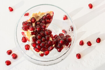 Pomegranate seeds close-up in a glass vase on a white background. Top view of the composition of pomegranate seeds. Bright sunlight, creative layout. The concept of freshness, summer, healthy food.