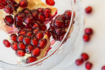 Pomegranate seeds close-up in a glass vase on a white background. Top view of the composition of pomegranate seeds. Bright sunlight, creative layout. The concept of freshness, summer, healthy food.