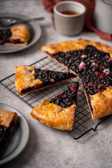 Sliced homemade blueberry galette, tart on the table with tea.