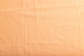 Fragment of smooth orange linen tissue. Top view, natural textile background.