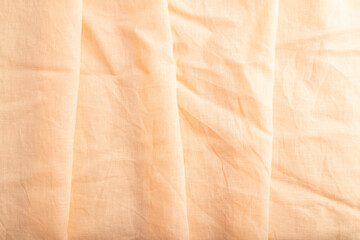 Fragment of orange linen tissue. Top view, natural textile background.