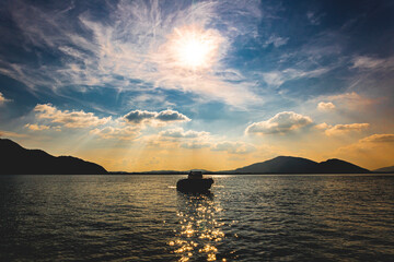 Silhouette of a boat standing on the water. Backlit with cloudy sky