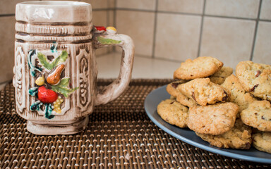 A plate with chocolate chips cookies and a colorful mug