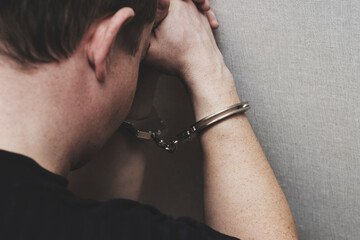 Man in handcuffs is praying for forgiveness. Chained by handcuffs man praying. Praying inmate