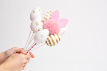 Top view of kids hand holding bouquet of decor eggs on a white background. Easter greeting card concept. Layout, flat lay, copy space composition.