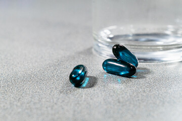 Medicamentos azules al lado de vaso de vidrio transparente