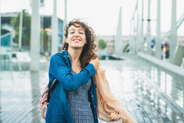 Young woman with curly hair smiling while it rains. Rainy day in late summer.