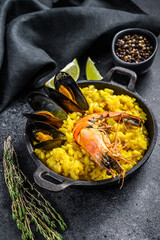 The Spanish paella with seafood prawns, shrimps, mussels. Black background. Top view