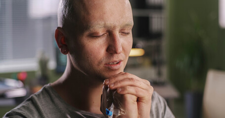 Bald man praying in oncology clinic