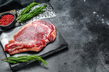 Fototapeta na wymiar Raw cowboy steak. Marble beef meat on the bone ribeye. Black background. Top view. Copy space
