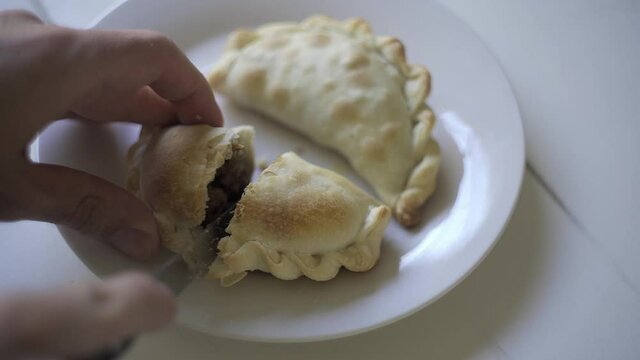 Close up of a knife cutting a recently baked warm empanada. Argentina