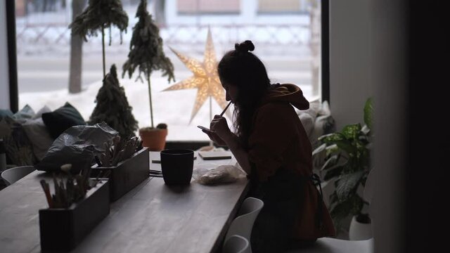Silhouette of potter woman working on details of a clay handcraft piece. Work with different pottery tools. Concept of creative leisure time and ceramics. Start up small business, artwork and interior