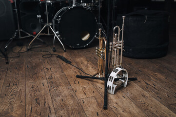 Fototapeta na wymiar A black drum kit and a microphone stand are on stage and next to them are two trumpets (alto and bass) and a white tambourine. The concept of a live concert of a jazz band.
