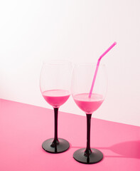 Delicious pink drink in two wineglasses on  pink and white background. Romantic concept