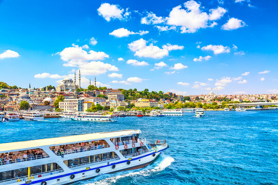 Touristic sightseeing ships in Golden Horn bay of Istanbul and view on Suleymaniye mosque with Sultanahmet district against blue sky and clouds. Istanbul, Turkey during sunny summer day.