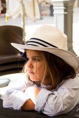 portrait of girl with hat seated, with background out of focus