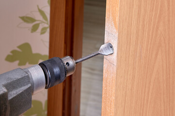 Locksmith use flat bit to wood when drilling hole for latch.