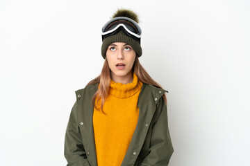 Skier caucasian woman with snowboarding glasses isolated on white background looking up and with surprised expression